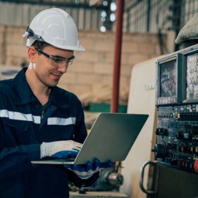 Técnico realizando manutenção preventiva em equipamento industrial, utilizando ferramentas para inspeção e ajuste.